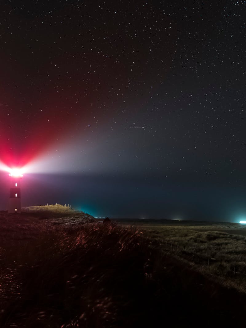 Lighthouse beacon beam against starry night sky